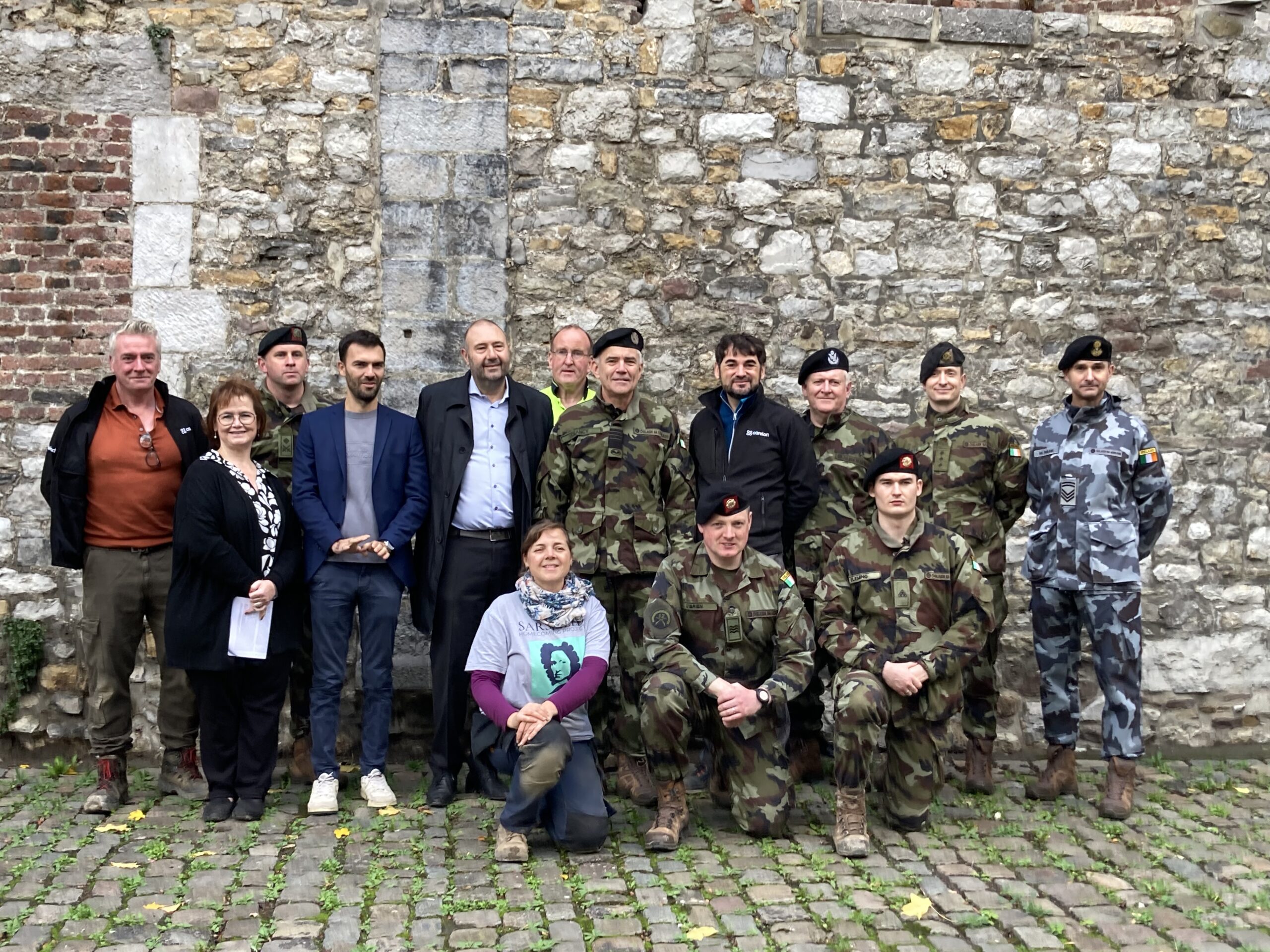 General Seán Clancy (center) with Mayor of Huy Christophe Colignon (to his right), Project Director Dr Loïc Guyon (to his left), the two soldiers from the 12th Infantry Battalion (kneeling at the front, Sergeant Dave O’Brien and Private James Fleming). Kneeling to the right of Sgt O’Brien is the project’s Forensic Anthropologist Dr Caroline Laforest. Behind the general is Archaeologist Dr Ger Riordan. On the second row, from the left are Assistant Archaeologist Neil O’Carroll, Huy Heritage Officer Stéphanie Ratz, Lt Col Conor Gorey and Huy Councillor Olivier Hublet. On the second row from the right are Warrant Officer Cian McParland, Col. Fiacra Keyes and Lt Col Tom Craven.