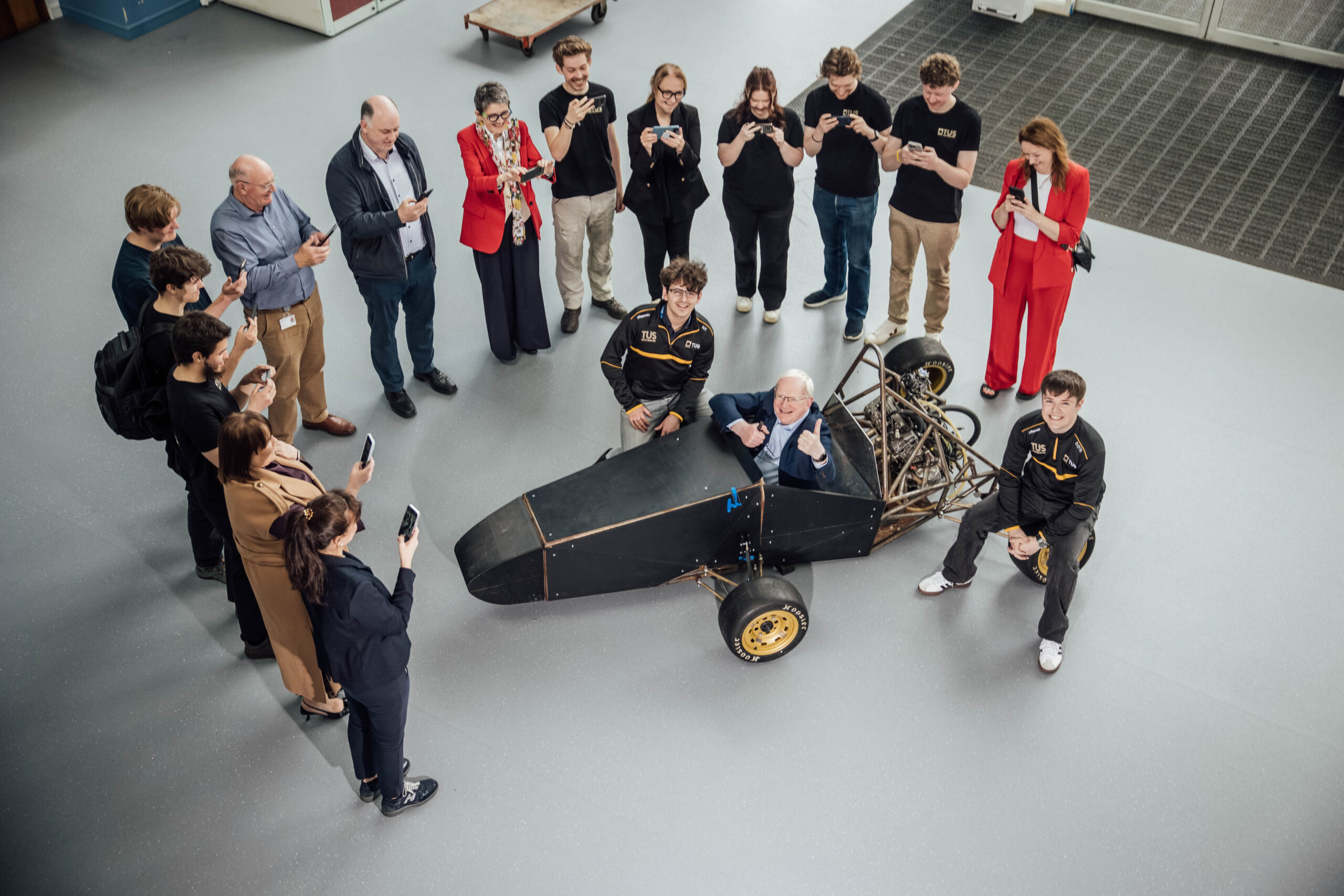 Professor Vincent Cunnance, President of TUS, gets into the driving seat of the Formula Car, beside Nathan Killane and Darragh O’Grady, of TUS Motorsport, surrounded by team members and TUS staff who have supported the project. tus motosport team
